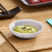 A small light gray round melamine ramekin filled with green paste and garnished with seeds.
