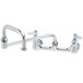 A chrome T&S wall mount faucet with two handles and a double joint nozzle.