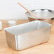 A Vollrath stainless steel bread loaf pan on a wood surface.