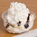 A Solo clear sundae cup filled with ice cream, chocolate syrup, and whipped cream.