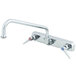 A chrome T&amp;S wall mount faucet with two handles and an 8" swing nozzle.