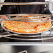 A person holding a pizza on an American Metalcraft pizza pan.