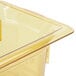 A Vollrath 1/6 size amber plastic food pan with a lid on a counter.