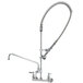 A silver T&S wall mounted pre-rinse faucet with curved hose.
