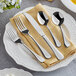 A five-piece set of Acopa Vittoria 18/8 stainless steel extra heavy weight flatware displayed on a folded beige napkin atop a white plate.