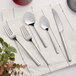 A five-piece set of stainless steel flatware including two forks, two spoons, and a knife, displayed on a white napkin.