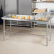 An Advance Tabco stainless steel sorting table with apples on it.