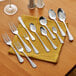 A set of stainless steel salad forks arranged on a yellow napkin with other cutlery on a wooden table.