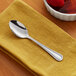 A stainless steel heavy weight teaspoon resting on a yellow napkin.