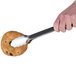 A hand using Tablecraft locking tongs to pick up a pastry.