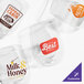 Four clear stemless wine glasses are shown, each featuring a different colorful custom logo or design printed on the front.