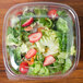 A Sabert clear flat lid on a plastic container of salad with strawberries and lettuce.