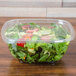 A salad in a Sabert clear plastic container with a clear flat lid.