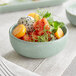 A small blue ceramic bowl filled with assorted fresh fruit and garnished with greens.