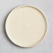 A round, off-white plate with a smooth matte finish, viewed from above on a light surface.