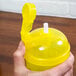 A person holding a yellow plastic container with a flip-top lid and straw.