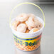 A white plastic bucket filled with mini donuts.
