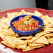 A plate of chips and salsa with a Carlisle cobalt blue salsa dish on a table.