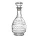 A clear, intricately cut glass decanter with a round stopper and decorative patterns.