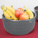 A Tablecraft gray cast aluminum bowl filled with bananas and apples.