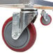 A metal cart with a pair of red and gray wheels, one of which is a metal wheel with a nut.