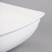 A close-up of a Tablecraft white cast aluminum oblong salad bowl with a white rim.