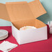 A white cardboard bakery box with an open lid containing a decorated cake.