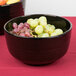 A black Tablecraft cast aluminum fruit bowl filled with grapes.