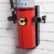 A Buckeye fire extinguisher mounted on a white wall using a red and black bracket.