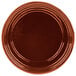 A copper cast aluminum souffle bowl with ridges on a brown plate.