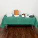 A table with food covered by a Creative Converting Hunter Green Tissue / Poly Table Cover.