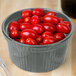 A Tablecraft gray cast aluminum souffle bowl filled with cherry tomatoes on a table.