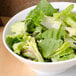 A CAC bone white porcelain salad bowl filled with lettuce and other salad ingredients.