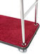 A stainless steel luggage cart with red carpet on the platform.
