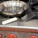 A Dexter-Russell solid turner with a plastic handle in a pan on a stove.