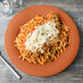 A GET Pumpkin Diamond Harvest melamine plate with spaghetti topped with cheese and meat.