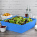 A Tablecraft blue speckle cast aluminum square bowl on a table with a blue container of salad inside.