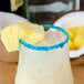 A glass with a Rokz Pina Colada cocktail rimmed with white sugar with a pineapple slice on top.