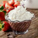 A glass bowl of chocolate pudding with whipped cream and strawberries in a Carlisle tulip dessert dish.