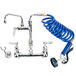 A T&S wall mount pet grooming faucet with a coiled hose and nozzle.