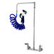 A T&S wall mount pet grooming faucet with a blue coiled hose and nozzle attached.