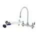 A white T&S deck mount pet grooming faucet with a gooseneck and angled spray valve, with hoses attached.