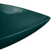 A close-up of a Tablecraft hunter green cast aluminum triangle display bowl with a curved edge.