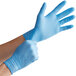 A pair of blue disposable nitrile exam gloves being worn on hands.
