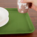 A hand holding a cup over a lime green Cambro tray.