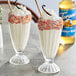 Two glasses of white liquid with Torani Sugar-Free Vanilla Bean syrup and sprinkles on top.