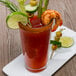 A glass of Clamato Original Tomato Cocktail with shrimp and vegetables on top.