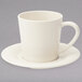 A Diamond Ivory melamine saucer with a white cup on a gray surface.