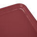 A red rectangular Cambro fiberglass tray with raspberry cream color on a table.