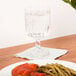 A Libbey Winchester goblet on a wood surface next to a plate of food.